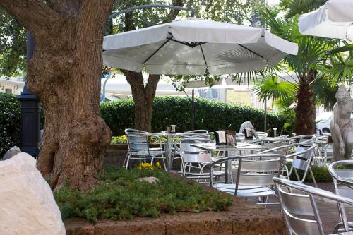 a row of tables and chairs under a white umbrella at Zara Rooms & Suites in Suzzara