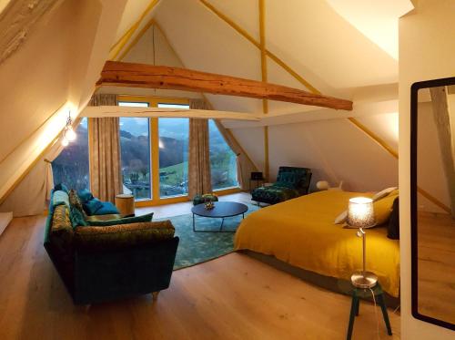 a attic bedroom with a bed and a large window at Le Chat Rouge Chambres d'Hôtes de Charme en Alsace in Orbey