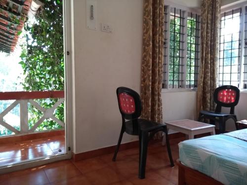a room with two chairs and a bed and a window at Coorg 4 C's Little Paradise in Madikeri