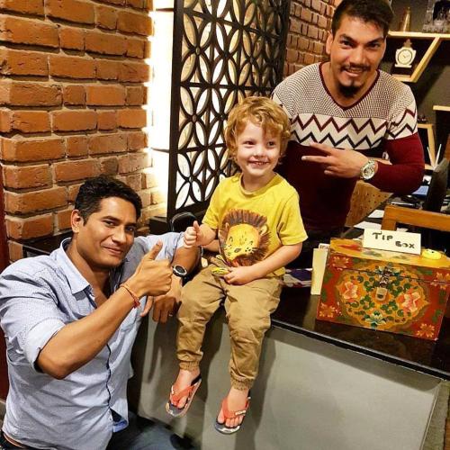 two men and a young boy sitting on a table at Utse Suites in Bengaluru