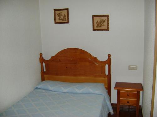 1 dormitorio con 1 cama con cabecero de madera y mesa en Casa Lopez, en San Martín del Castañar