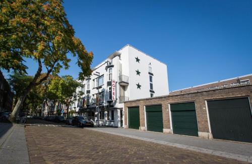 a white building with green garage doors on a street at Hotel Breitner in Rotterdam