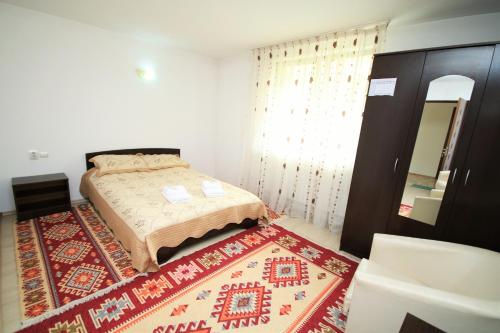 a small bedroom with a bed and a rug at Pensiunea Ciobanelu in Malaia