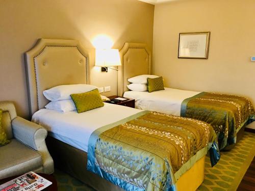 a hotel room with two beds and a chair at Taj Samudra, Colombo in Colombo