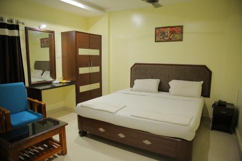 Un dormitorio con una cama y una silla azul. en Hotel Siddhartha, en Guntūr
