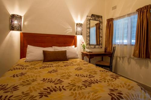 a bedroom with a bed and a desk and a mirror at Ravine Lodge in Livingstone
