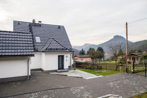 a white house with a black roof and a fence at Weinberghaus Prossen in Bad Schandau