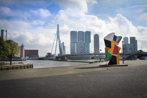 a sculpture in front of a river with a bridge at Hotel Breitner in Rotterdam
