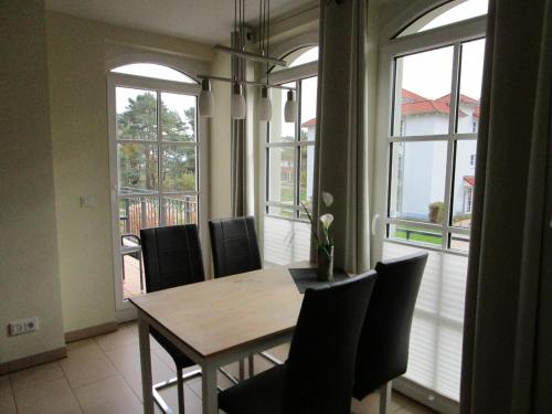 a dining room with a table and chairs and windows at Haus Meeresblick Wohnung A 1.04 in Baabe