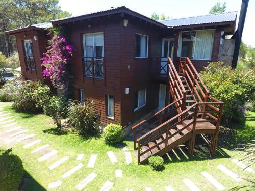 a house with two large wooden chairs in the yard at Cabañas Mellmell in Mar de las Pampas