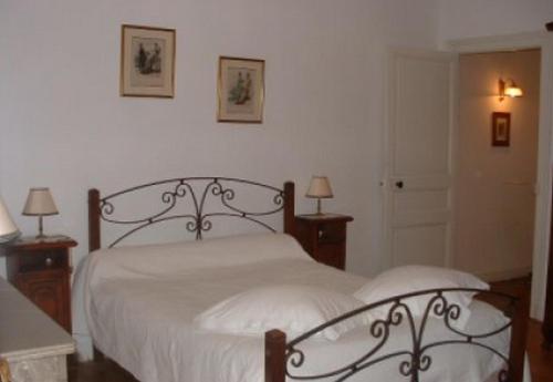 a bedroom with a bed with white sheets and two lamps at Chambres d'hôtes Le Pont Romain in Montfort-le-Gesnois