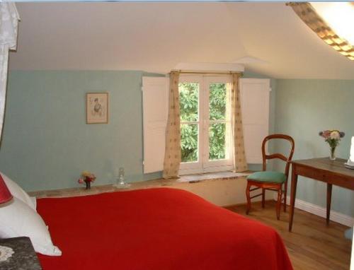 1 dormitorio con cama roja, escritorio y ventana en Chambres d'hôtes Le Pont Romain, en Montfort-le-Gesnois