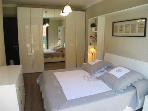 a bedroom with a large white bed and a mirror at Appartamento Cicci Bello in Ghiffa