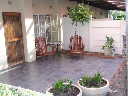 a patio with two chairs and a table on a house at Old Coach Road Guest House in Barberton