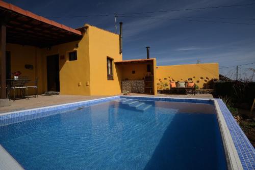 a villa with a swimming pool in front of a house at Finca La Majadera in El Rosario