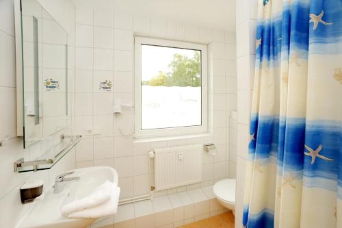 uma casa de banho com um lavatório, um WC e uma janela. em Lübsche Thorweide em Wismar