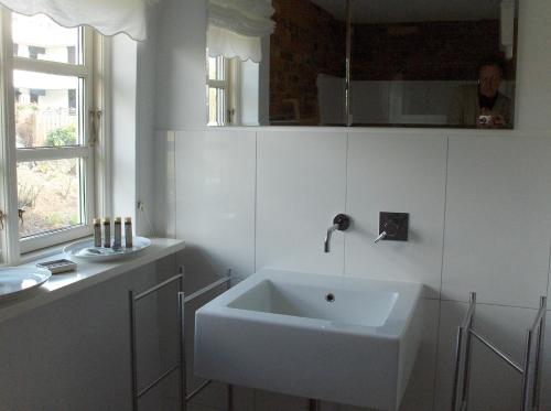 ein weißes Badezimmer mit einem Waschbecken und einem Spiegel in der Unterkunft CARLS KATE in Grömitz an der Ostsee in Grömitz