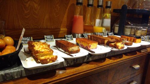 a buffet with different types of cakes on plates at Garlande Hôtel Avignon Centre in Avignon