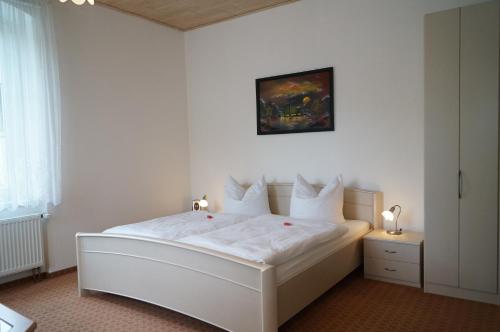 Un dormitorio con una cama blanca con sábanas y almohadas blancas. en Villa Angelika, en Kurort Altenberg