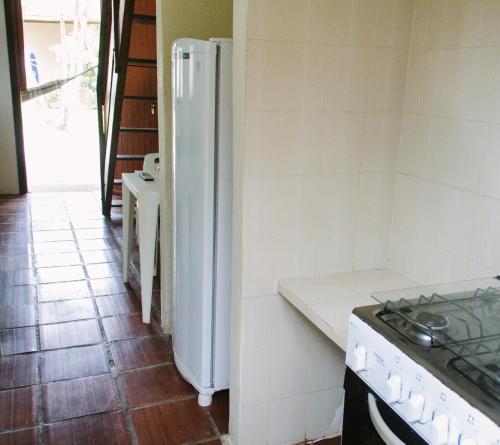 a kitchen with a white refrigerator and a stove at Arco Iris Chales II in Maresias