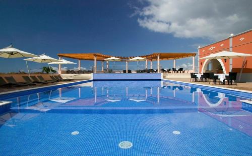 a swimming pool with chairs and umbrellas on a building at Luxury two bedroom Palheiro Village by Holiday Rental Madeira in Funchal