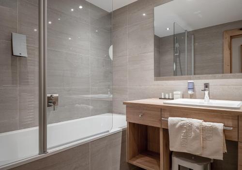 a bathroom with a tub and a sink and a shower at Hotel Alpenland in Obergurgl