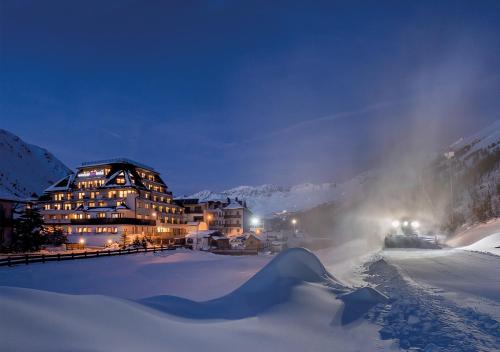 a large building in the snow at night at Hotel Alpenland in Obergurgl