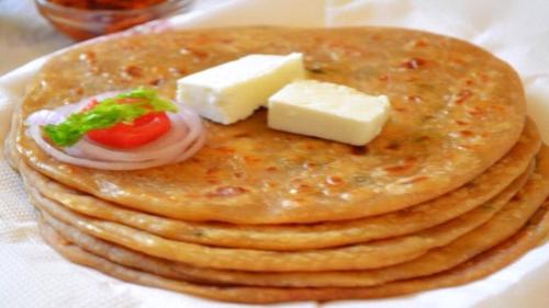a stack of pancakes with cheese and a tomato at Hotel Sun Village Near New Delhi Railway Station in New Delhi