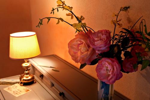 a vase of flowers on a table next to a lamp at Fattoria Poggerino in Radda in Chianti