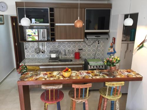 a kitchen with a table with bar stools at Apartamento 05 Vivendas do Serrano - Lençóis in Lençóis