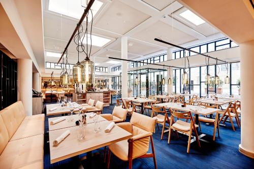 コペンハーゲンにあるNobis Hotel Copenhagen, a Member of Design Hotels™の木製のテーブルと椅子、窓のあるレストラン
