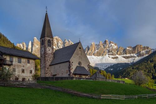 a church on a hill in front of a mountain at Jaiterhof in Funes