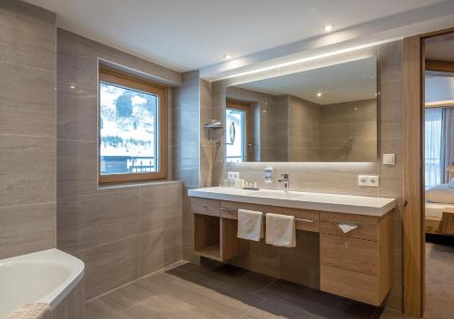 een badkamer met een wastafel, een bad en een spiegel bij Apartment Alpenland in Obergurgl
