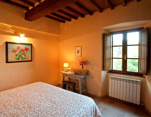 a bedroom with a bed and a window and a table at Fattoria Poggerino in Radda in Chianti