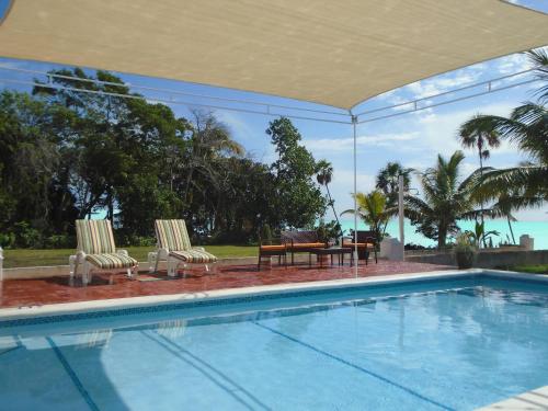 a swimming pool with two chairs and a table at Serenity Sands in Corozal