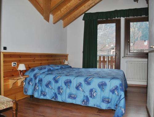 ピンツォーロにあるRendena Ski Apartmentsのベッドルーム1室(青い掛け布団、窓付)