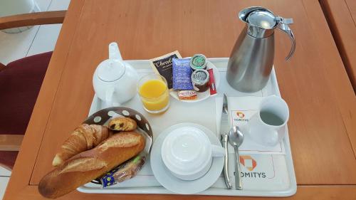 een dienblad met een ontbijt van croissants en jus d'orange bij Domitys La Plage de Nacre in Courseulles-sur-Mer