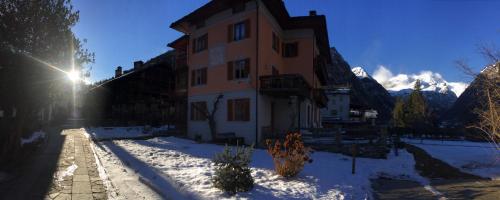 a building in the snow with the sun in the background at Tre Alberi Liberi in Alagna Valsesia