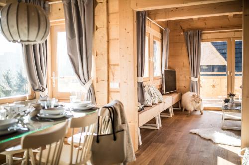 a dining room with a table and chairs and a television at Osada domków TATRA-DREAM in Zakopane