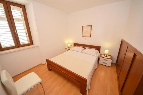 1 dormitorio con 1 cama, 1 silla y 1 ventana en Apartments Bradičić en Orebić