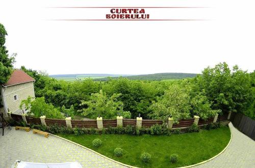 a garden with a wooden fence and green grass at Curtea Boierului Hotel in Peresecina