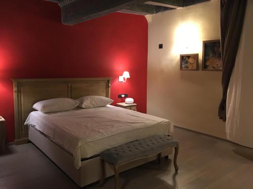 um quarto com paredes vermelhas e uma cama com um banco em Visione Strada Maggiore 62 em Bolonha