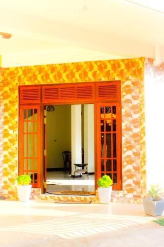 a building with orange doors and plants in front at The City Tourist Hotel in Anuradhapura