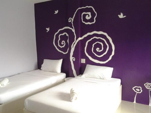 2 camas en una habitación con un cuadro en la pared en Sukwimol Place, en Phitsanulok