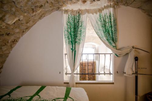 ein Schlafzimmer mit einem Bett und einem Fenster mit Vorhängen in der Unterkunft Il Nido Bianco in Ostuni