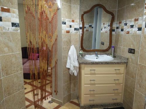 uma casa de banho com um lavatório e um chuveiro com um espelho. em appartement Annakhil em Marrakech