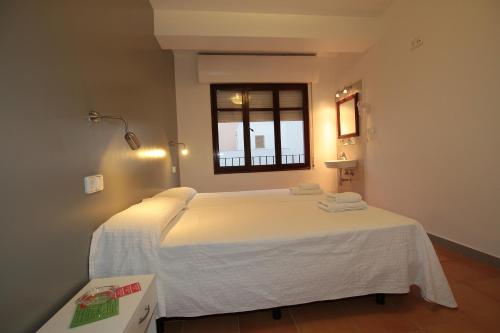 a bedroom with a large white bed with a window at Hostal Ripoll Ibiza in Ibiza Town