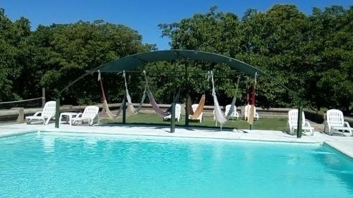 a swimming pool with chairs and a swing at Chacras de Azcona Hostería in Azul