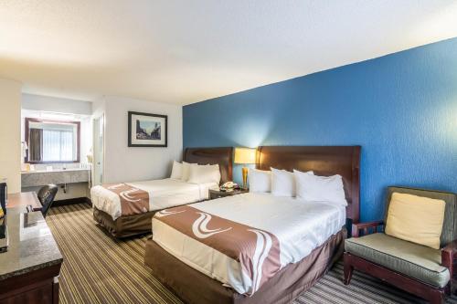 una habitación de hotel con 2 camas y una silla en Rest and Relax Inn en Pensacola