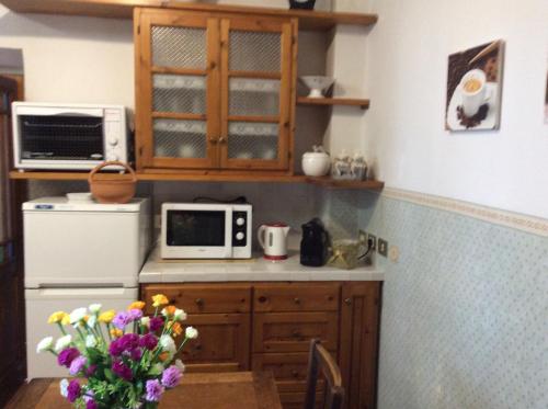 a kitchen with a microwave and a table with flowers at Casa Vacanze Amelia in Fiesole